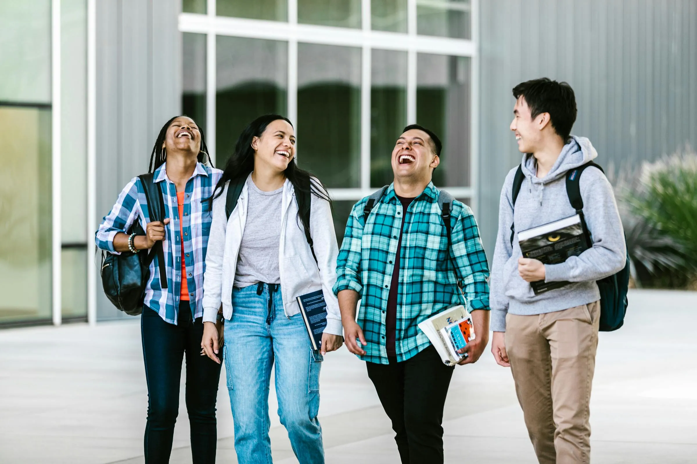 Group of diverse college students laughing and walking together on campus